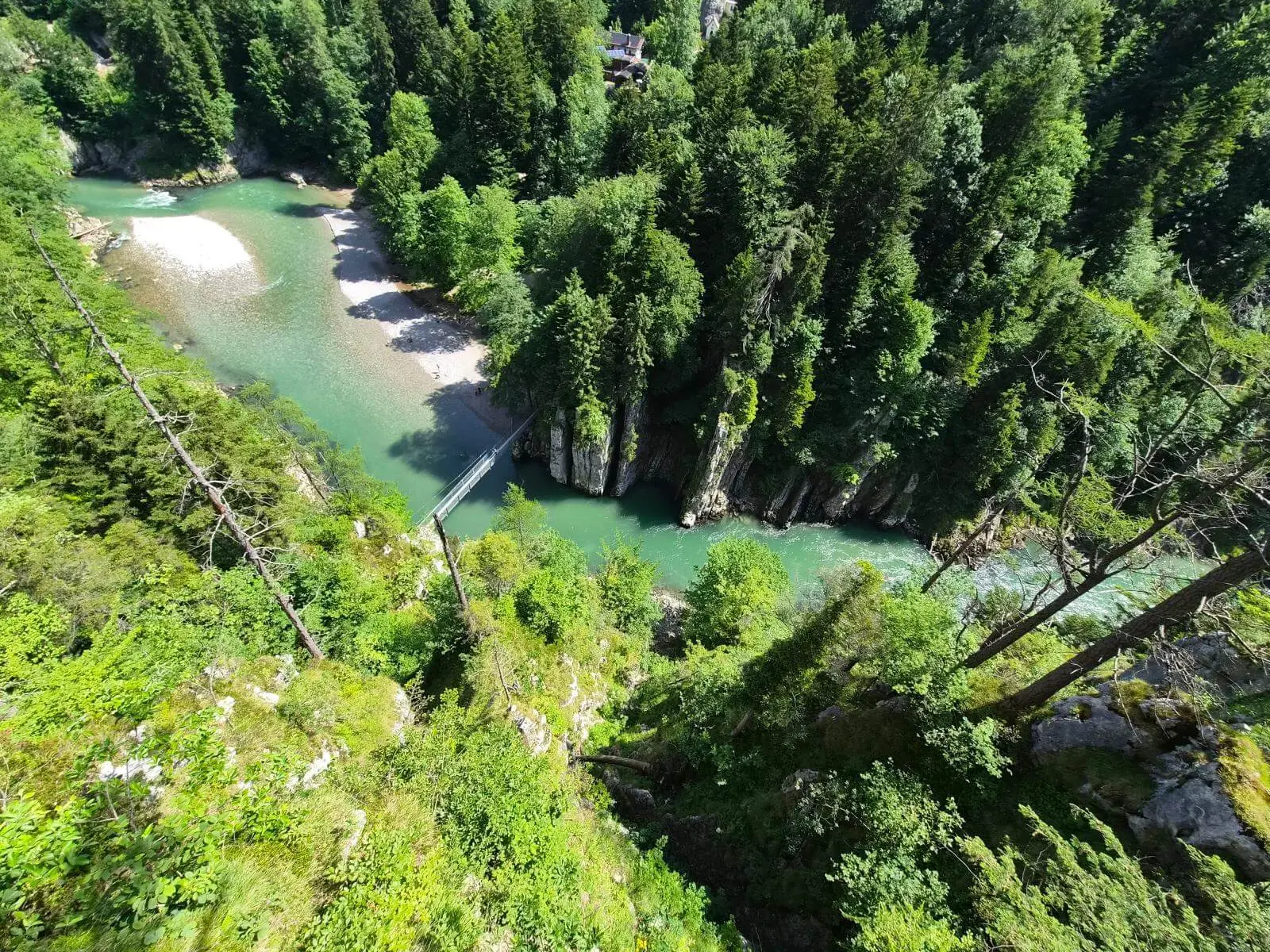 Tiefblick auf die Entenlochklamm mit türkisgrünem Fluss, steilen Felswänden, dichter Bewaldung und einer Hängebrücke. | © DAV Markt Schwaben / Hubert Inhofer