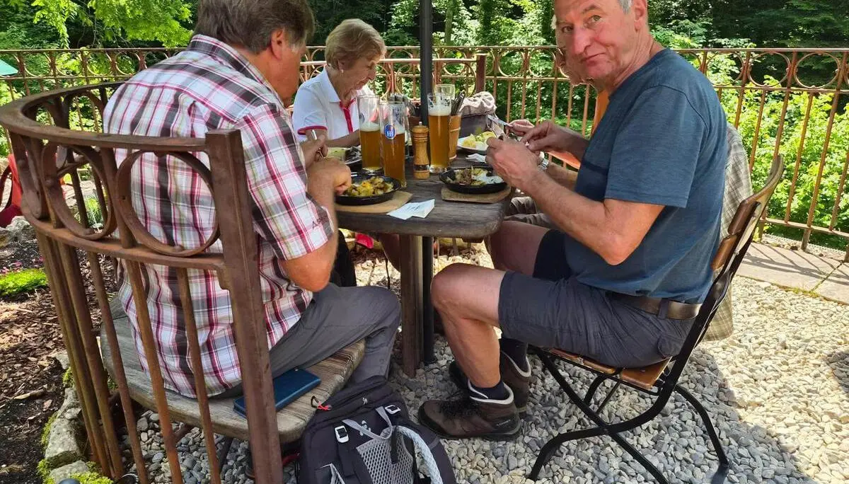 Wandernde sitzen nach der Tour an einem Tisch im Biergarten des Gasthauses Klobenstein und stärken sich bei einer Mahlzeit. | © DAV Markt Schwaben / Hubert Inhofer
