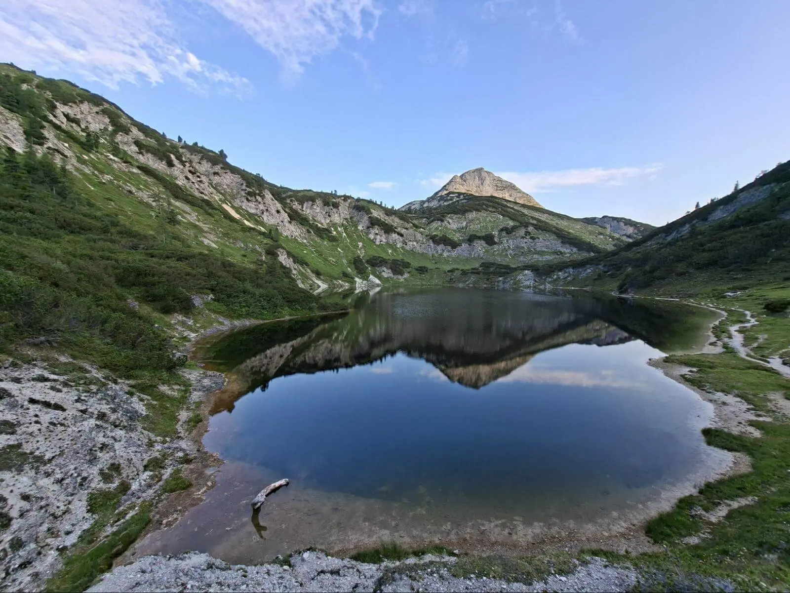 Ein ruhiger Bergsee spiegelt einen markanten Gipfel und die umliegenden Hänge. Uferwege und Karstfelsen säumen das klare Wasser. Show more lines Provide your feedback on BizChat | © DAV Markt Schwaben/Alfred Quiel