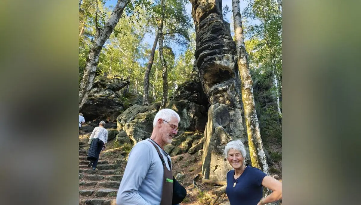 Zwei Wandernde stehen vor einer markanten Sandsteinfelsnadel im Wald; eine Steintreppe führt zwischen Birken zum Felsen. | © DAV Markt Schwaben/Erwin&Ursula Matzinger