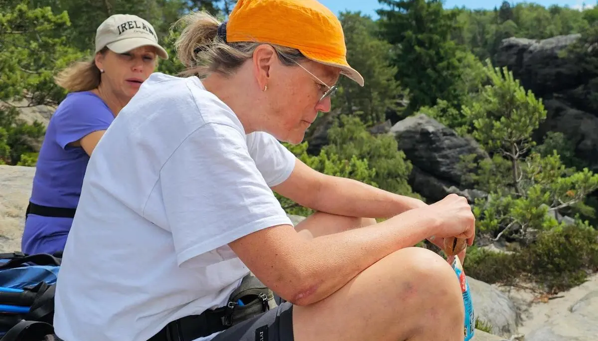 Zwei Wandernde sitzen während einer Pause auf einem Sandsteinfelsen. Im Hintergrund liegen Kiefern, Felsen und bewaldete Hänge der Sächsischen Schweiz. | © DAV Markt Schwaben/Lutz Gründel