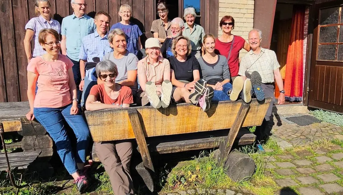 Die Tourengruppe versammelt sich für ein Gruppenfoto vor einem Gebäude der Dessauer Hütte. Einige Personen sitzen auf einer großen Holzbank, andere stehen dahinter im Sonnenlicht. | © DAV Markt Schwaben/Lutz Gründel