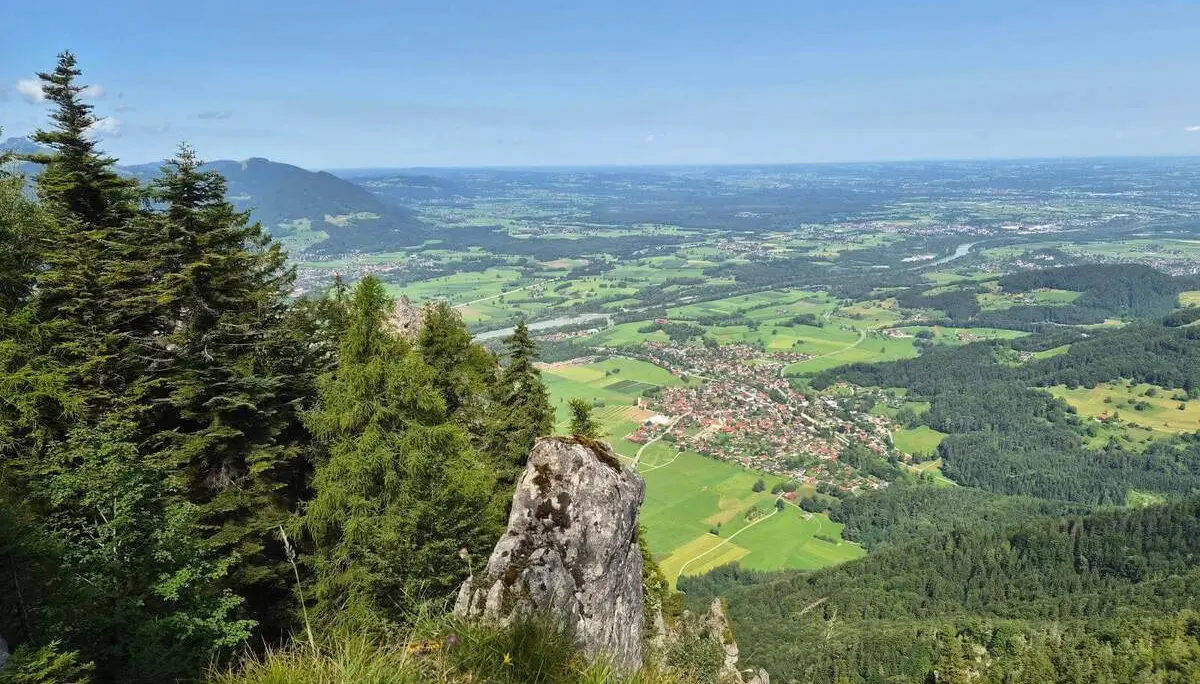 Blick von einem felsigen Aussichtspunkt über das Inntal mit Wäldern, Feldern und Ortschaften. Im Vordergrund stehen Felsen und Nadelbäume. | © DAV Markt Schwaben / Hubert Inhofer