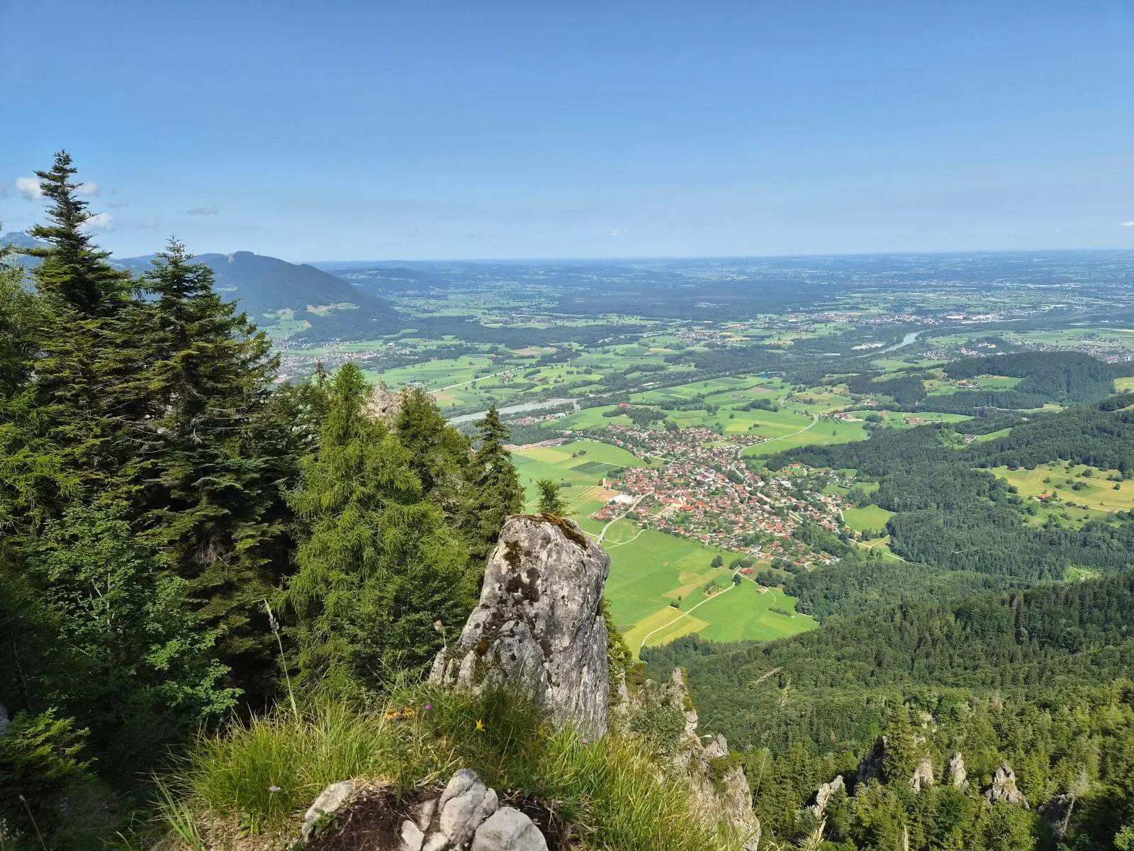 Blick von einem felsigen Aussichtspunkt über das Inntal mit Wäldern, Feldern und Ortschaften. Im Vordergrund stehen Felsen und Nadelbäume. | © DAV Markt Schwaben / Hubert Inhofer