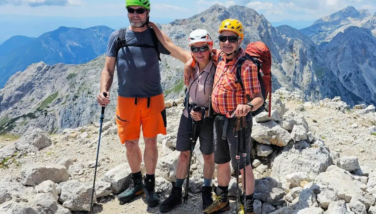 Drei Personen mit Helmen und Wanderstöcken stehen auf dem felsigen Gipfel der Ojstrica. Im Hintergrund erstreckt sich die Bergwelt der Steiner Alpen. | © DAV Markt Schwaben/Lutz Gründel