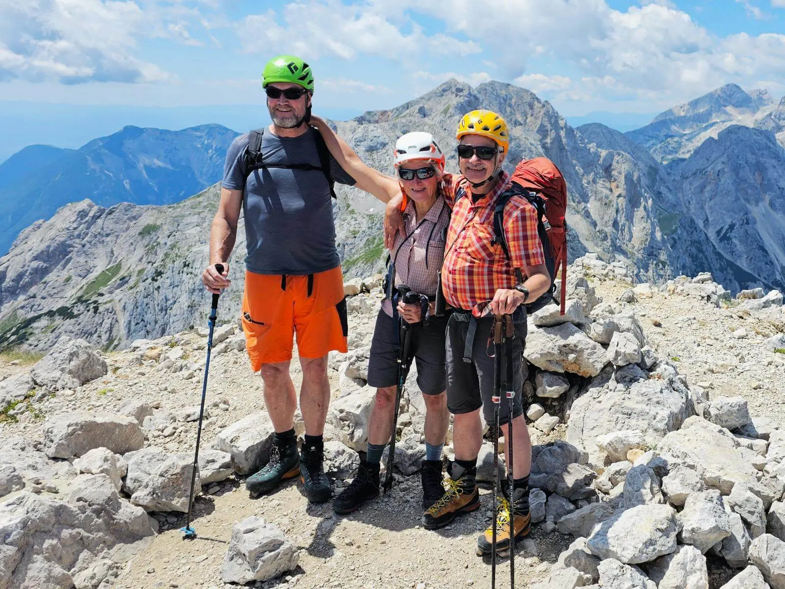 Drei Personen mit Helmen und Wanderstöcken stehen auf dem felsigen Gipfel der Ojstrica. Im Hintergrund erstreckt sich die Bergwelt der Steiner Alpen. | © DAV Markt Schwaben/Lutz Gründel