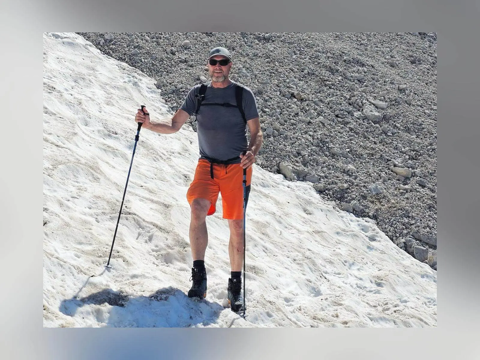 Eine Person überquert mit Wanderstöcken ein Schneefeld im steilen Kalkgelände. Daneben erstreckt sich eine graue Schutthalde aus Felsgeröll. | © DAV Markt Schwaben/Lutz Gründel