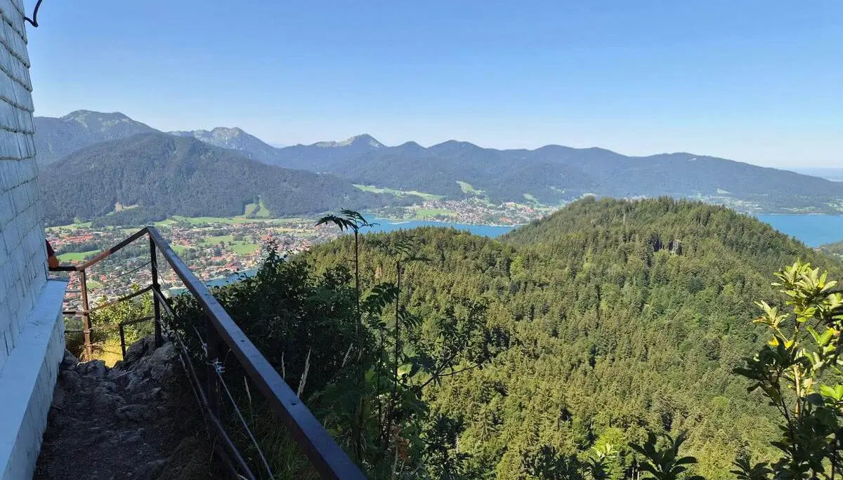 Blick von der Riedersteinkapelle über bewaldete Hügel, den Tegernsee und die umliegenden Berge bei klarem Sommerwetter. | © DAV Markt Schwaben/Hubert Inhofer