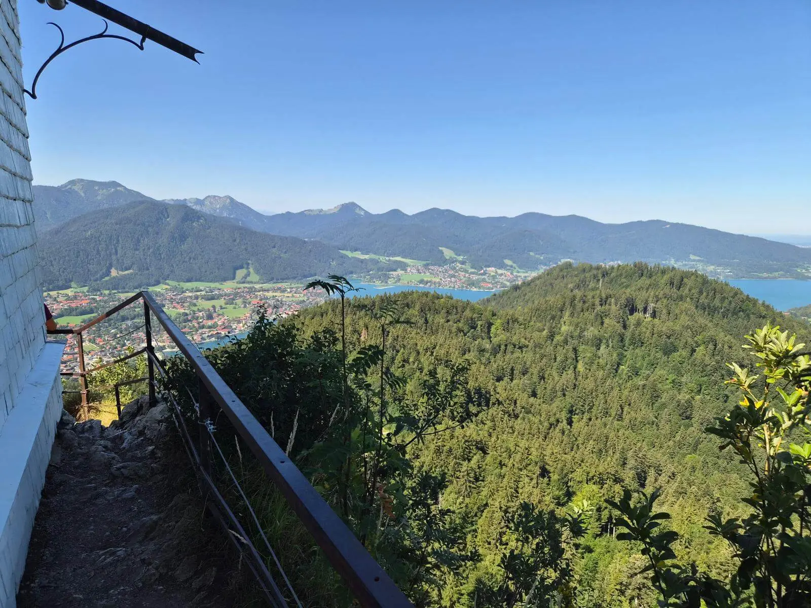 Blick von der Riedersteinkapelle über bewaldete Hügel, den Tegernsee und die umliegenden Berge bei klarem Sommerwetter. | © DAV Markt Schwaben/Hubert Inhofer