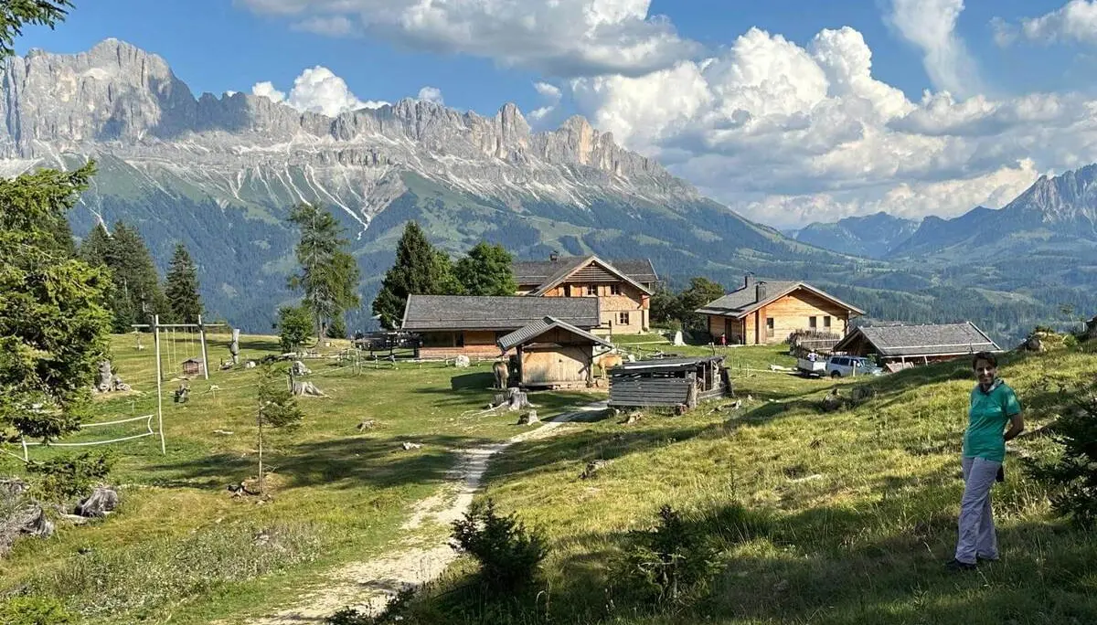 Almgelände mit Tschafon-Hütte und Nebengebäuden vor den Felswänden des Rosengartens; ein Weg führt über die Bergwiese. | © DAV Markt Schwaben/Christa Groß