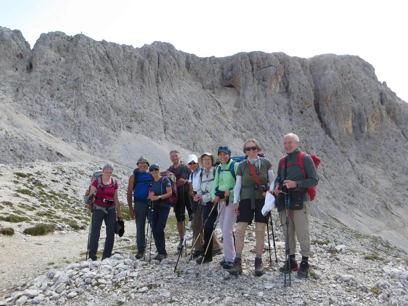 Wandergruppe mit Trekkingstöcken steht auf einem steinigen Pfad unter einer mächtigen Felswand im Rosengartengebiet. | © DAV Markt Schwaben/Gerlinde Hübl