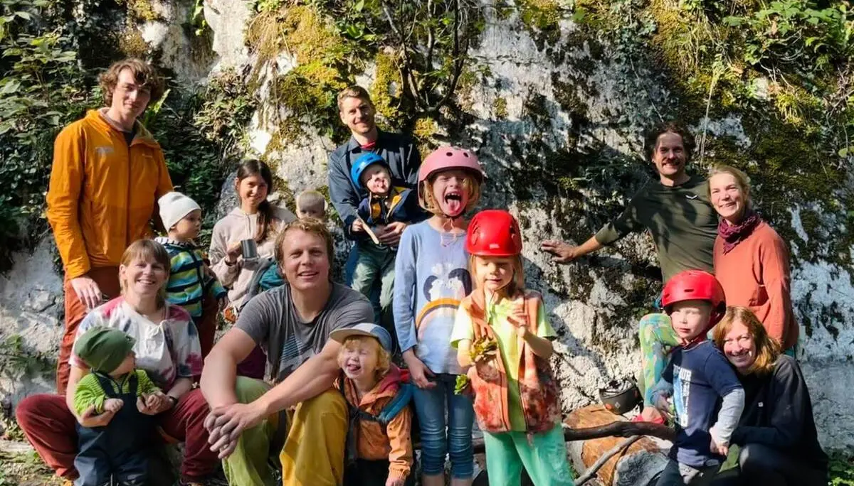 Familiengruppe mit Kindern in Kletterhelmen vor einer Felswand. Die Teilnehmenden machen am Klettergarten Auer Wandl Rast. | © DAV Markt Schwaben/Lara Wolff