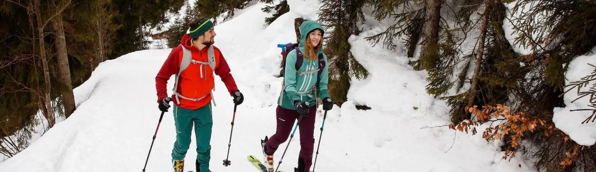 Zwei Personen steigen mit Tourenski durch verschneiten Wald bergauf; winterliche Szene als Teaser für Skitouren‑Ausrüstung. | © DAV / Marco Kost 2019