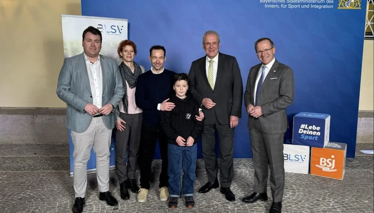Sechs Personen stehen vor blauem Hintergrund mit Logos des bayerischen Innenministeriums und Sportverbänden; sie posieren für ein offizielles Foto. | © BLSV/​Hermann