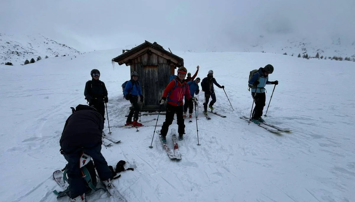 Skitourengruppe bereitet sich vor der kleinen Holzhütte auf die Abfahrt vor; eine Person beim Abfellen im Vordergrund. | © DAV Markt Schwaben · Foto: Markus Sellmeier