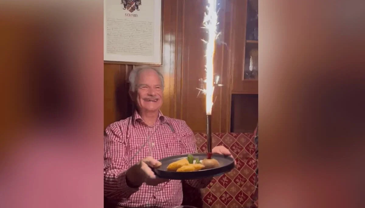 Lutz sitzt abends in holzgetäfelter Stube und hält ein Dessert mit Wunderkerze; festliche Stimmung und warmes Licht. | © DAV Markt Schwaben · Foto: Edith Zerrle