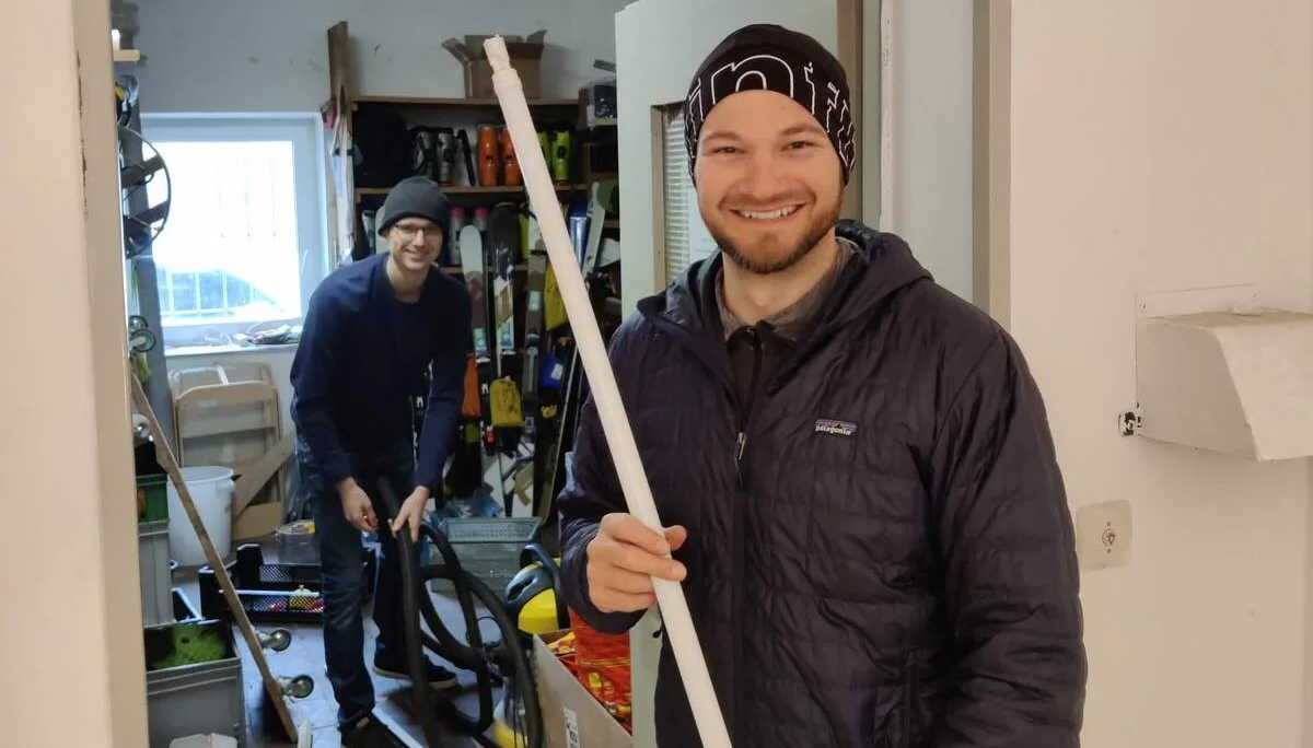 Zwei Personen im Materiallager, die Person im Vordergrund hält eine Leuchtstoffröhre, beide lächeln. | © DAV Markt Schwaben