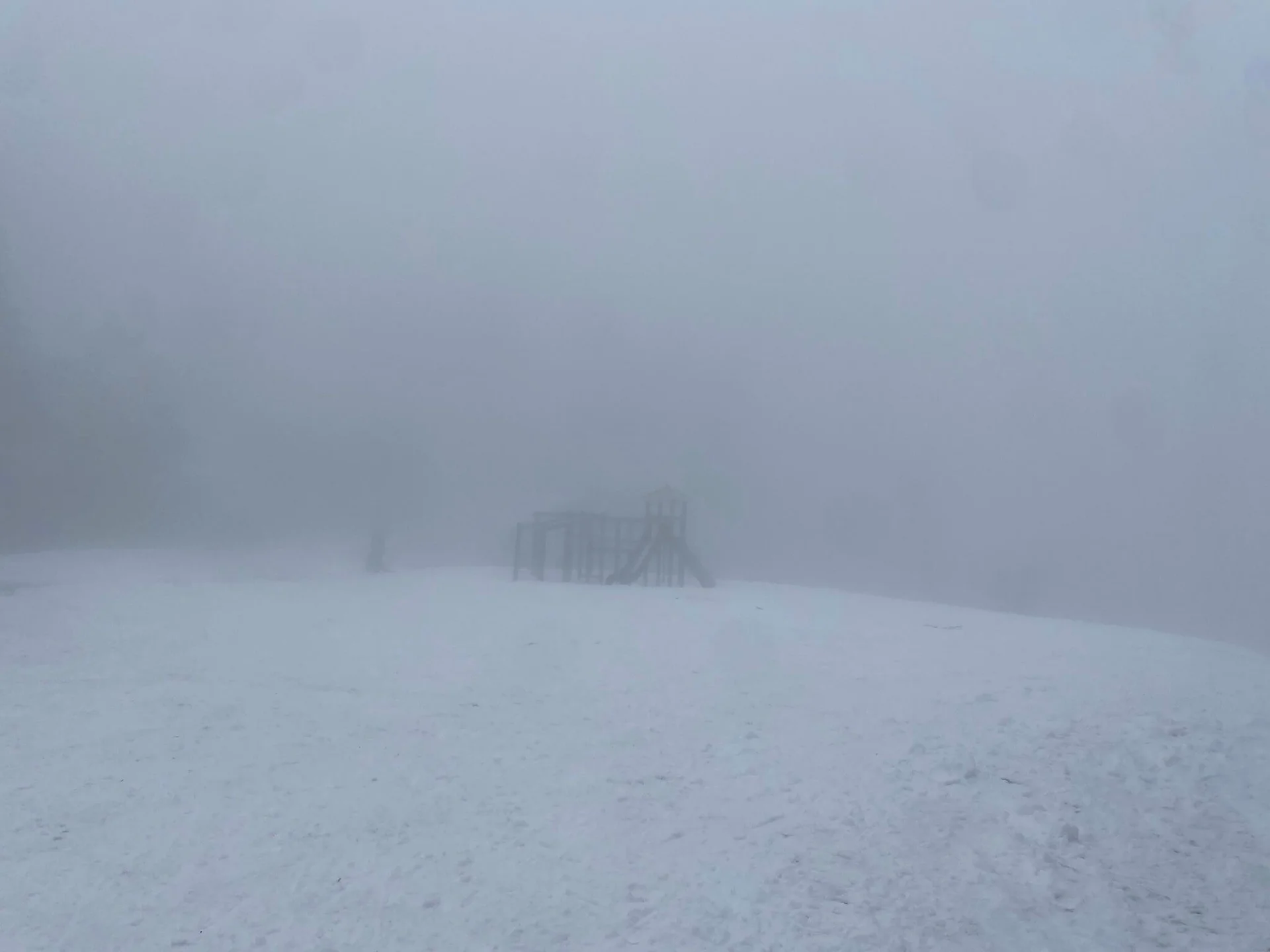 Spielplatzstruktur mit Rutsche und Kletterelementen, umgeben von Schnee und dichtem Nebel für eine mystische Atmosphäre. | © DAV Markt Schwaben