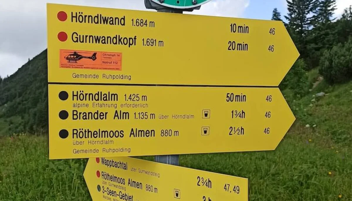 Gelbe Wanderschilder bei Ruhpolding zeigen Wanderwege und Zeiten zur Hördlwand, Almen und Seenregion. | © DAV Markt Schwaben