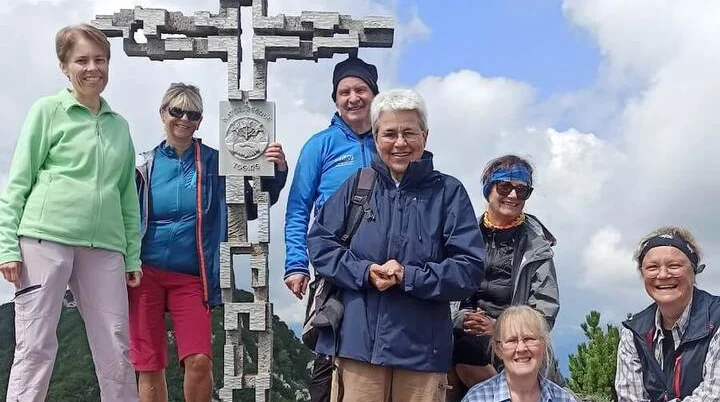 Sieben Erwachsene posieren am Gipfelkreuz der Hördlwand. | © DAV Markt Schwaben