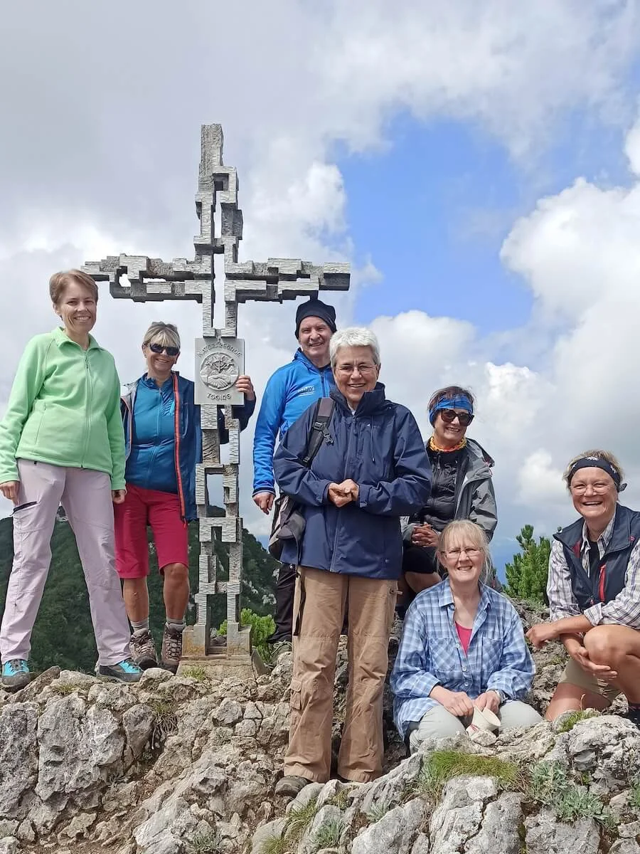 Sieben Erwachsene posieren am Gipfelkreuz der Hördlwand. | © DAV Markt Schwaben