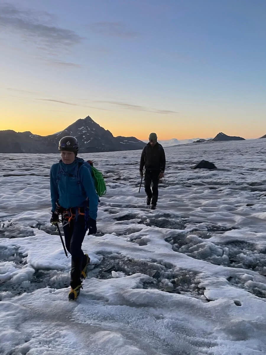 Zwei Bergsteiger durchqueren einen verschneiten Gletscher in den Westalpen bei Sonnenaufgang – Berge und Ausrüstung im Fokus. | © DAV Markt Schwaben | Christian Reischl
