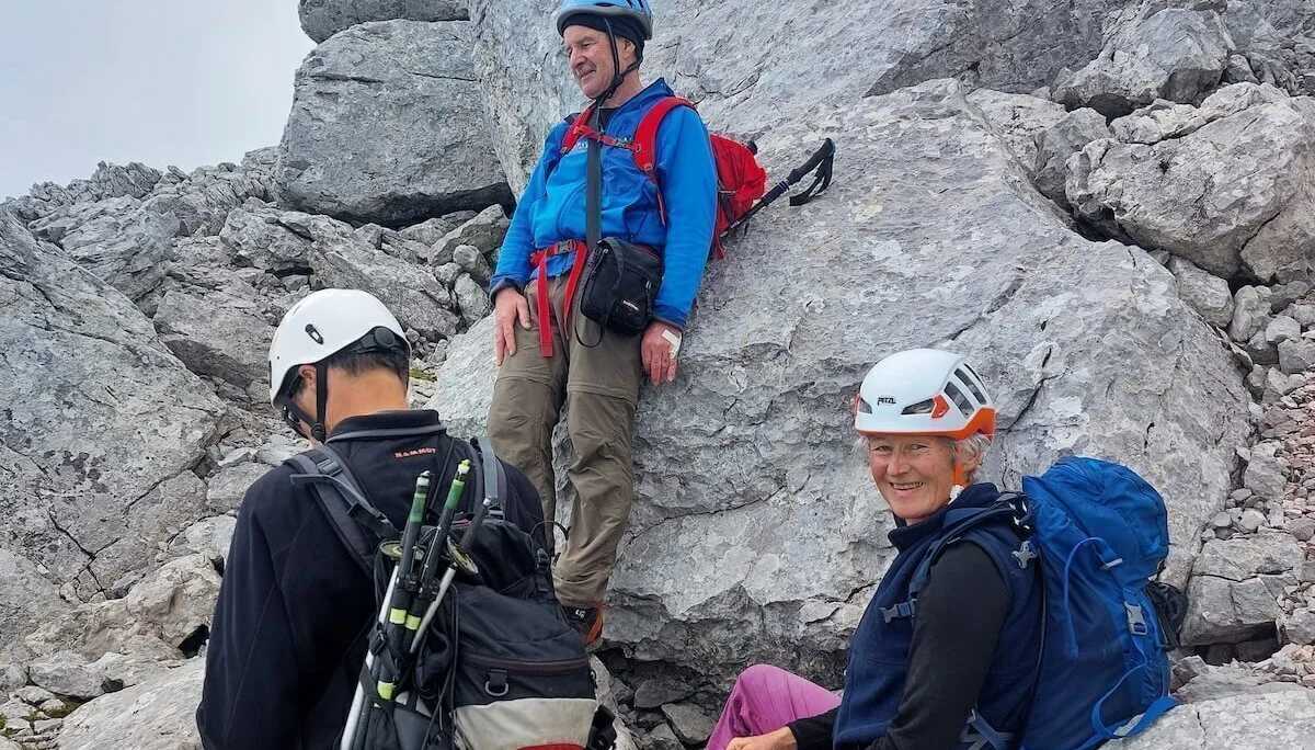 Drei Bergsteiger rasten auf felsigem Grat, einer sitzt lächelnd, hinten steiles Gelände und Waldhang. | © DAV Markt Schwaben · Foto: Lutz Gründel