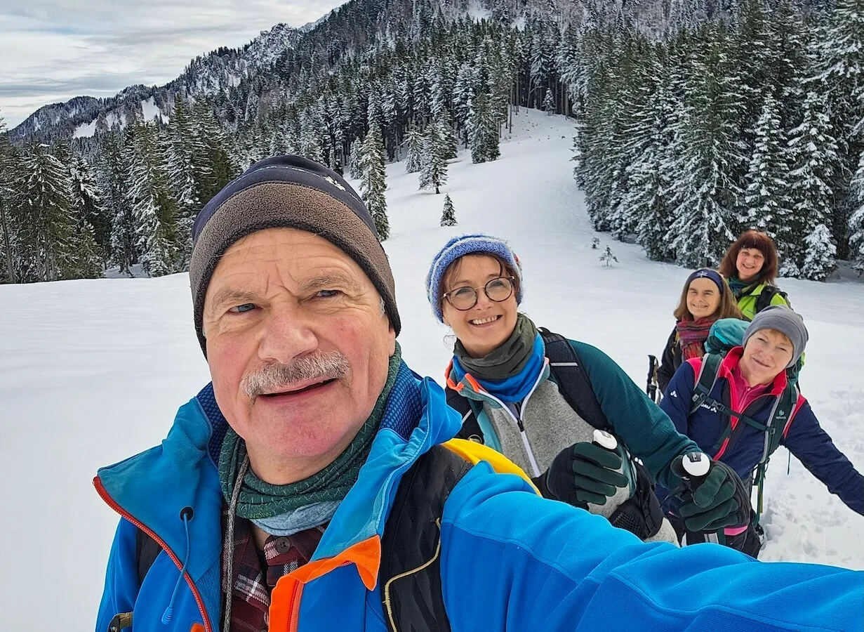 Fünf Wandernde posieren für ein Selfie im Schnee; im Hintergrund verschneite Tannen und Berge unter blauem Himmel. | © DAV Markt Schwaben | Foto: Lutz Gründel