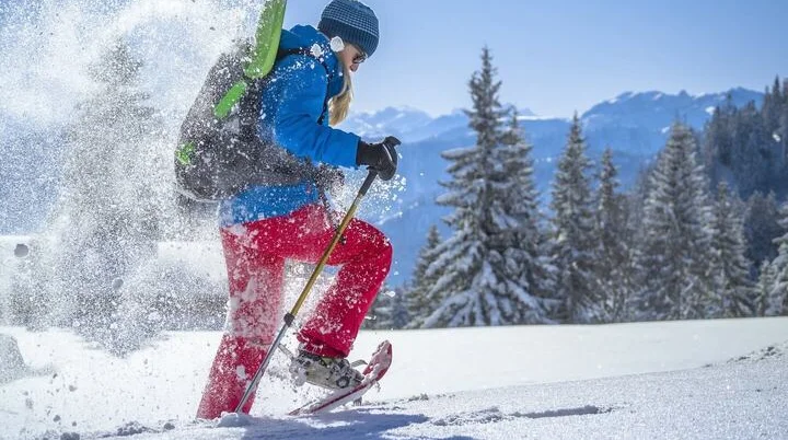 Eine Person mit Schneeschuhen unterwegs in verschneiter Berglandschaft bei klarem Winterwetter. | © DAV/Silvan Metz