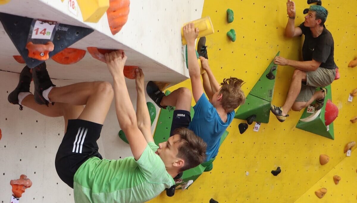 Drei Kletterer erklimmen verschiedene Routen an einer Boulderwand mit bunten Griffen. | © DAV Markt Schwaben | Foto Uwe Rauschenbach