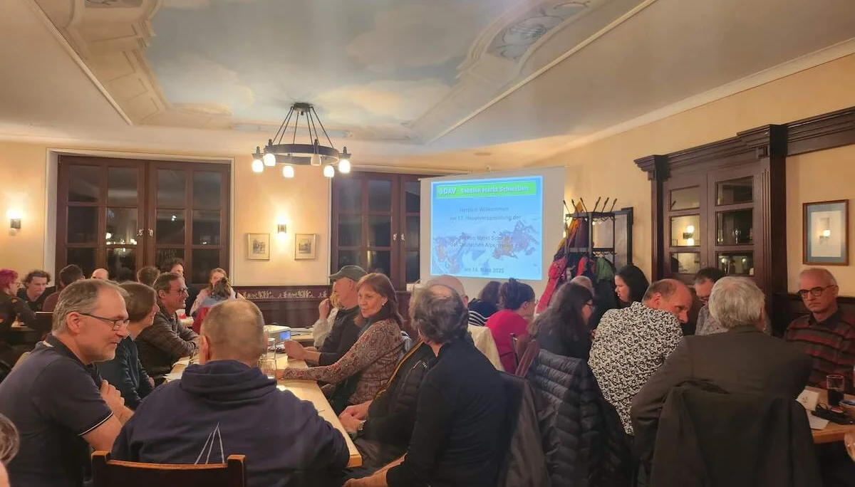 Mitglieder der DAV-Sektion Markt Schwaben sitzen an Tischen in einem Tagungsraum und verfolgen eine Präsentation während der jährlichen Mitgliederversammlung.“ | © DAV Markt Schwaben | Foto Anna Thoms