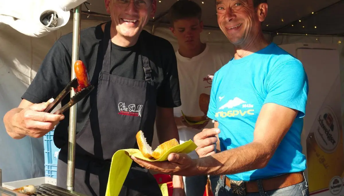 Eine Band spielt am Abend auf einer kleinen Bühne unter einem blauen Pavillon, beleuchtet von farbigen Scheinwerfern. | © DAV Markt Schwaben/Thomas Schäffler
