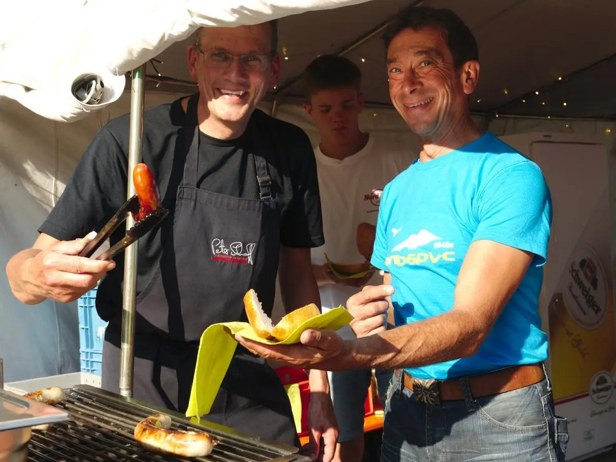 Eine Band spielt am Abend auf einer kleinen Bühne unter einem blauen Pavillon, beleuchtet von farbigen Scheinwerfern. | © DAV Markt Schwaben/Thomas Schäffler