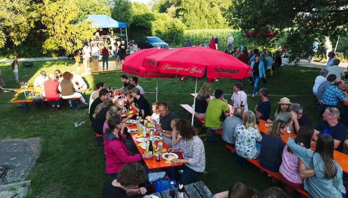 Besucher tanzen auf einer gelben Holzplattform, während andere an Tischen sitzen und der Kletterturm im Hintergrund sichtbar ist. | © DAV Markt Schwaben/Thomas Schäffler 2018
