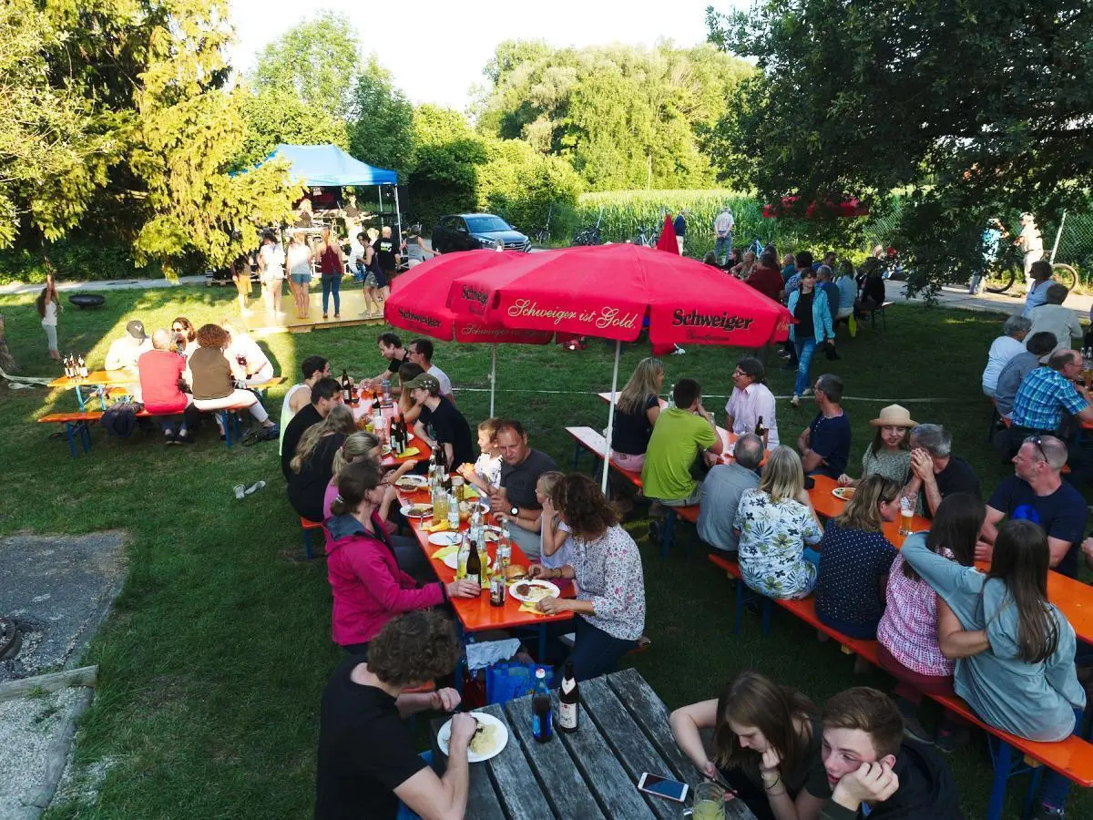 Besucher tanzen auf einer gelben Holzplattform, während andere an Tischen sitzen und der Kletterturm im Hintergrund sichtbar ist. | © DAV Markt Schwaben/Thomas Schäffler 2018