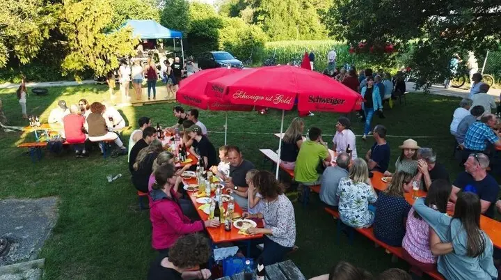 Besucher tanzen auf einer gelben Holzplattform, während andere an Tischen sitzen und der Kletterturm im Hintergrund sichtbar ist. | © DAV Markt Schwaben | Foto: Thomas Schäffler