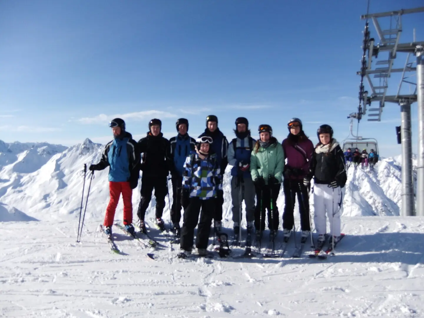 Jugendgruppe steht mit Skiausrüstung auf einem verschneiten Hang; im Hintergrund Sessellift und Bergpanorama bei klarem Himmel. | © DAV Markt Schwaben