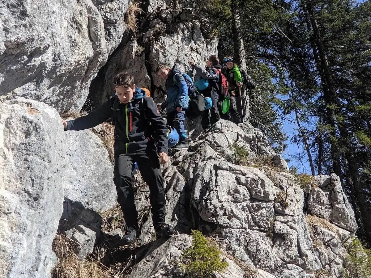 Mehrere Jugendliche steigen mit Rucksäcken über steinigen Bergpfad; Felsblöcke und Kiefern im Hintergrund. | © DAV Markt Schwaben | Foto Florian Kaiser 2024