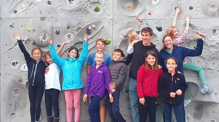 Kinder klettern an künstlicher Felswand – bunte Griffe, Helme und Teamgeist bei spannendem Jugendgruppen-Training. | © DAV Markt Schwaben | Foto Anna Maria Blau