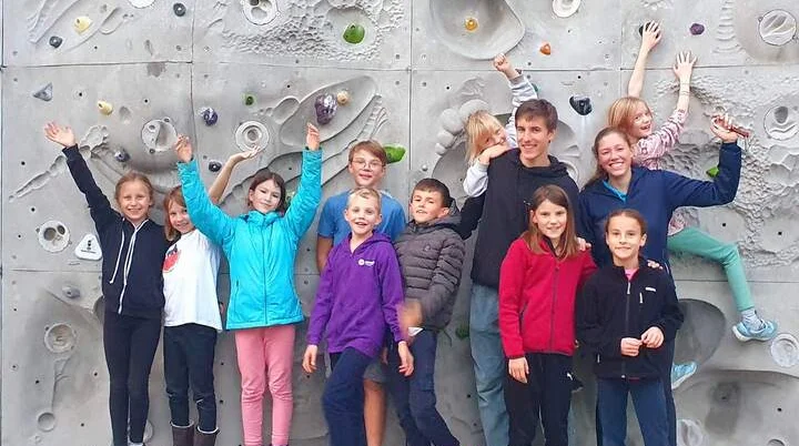 Kinder klettern an künstlicher Felswand – bunte Griffe, Helme und Teamgeist bei spannendem Jugendgruppen-Training. | © DAV Markt Schwaben | Foto Anna Maria Blau