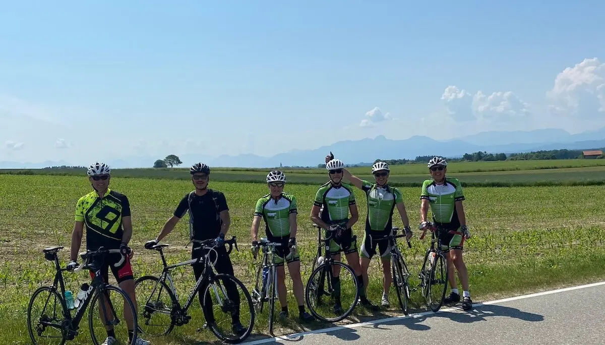 Gruppe von Radfahrer steht mit ihren Rädern am Straßenrand; im Hintergrund Felder, Berge und klarer Himmel. | © DAV Markt Schwaben