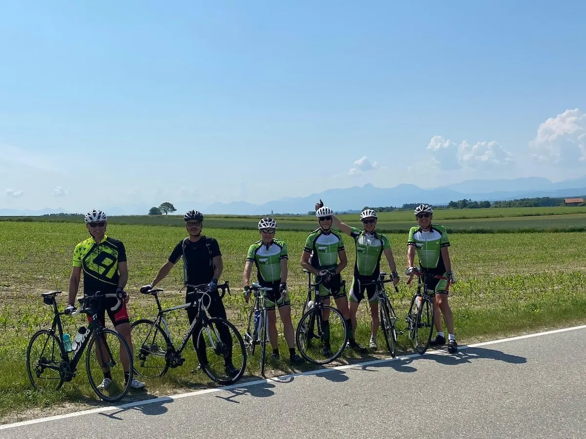 Gruppe von Radfahrer steht mit ihren Rädern am Straßenrand; im Hintergrund Felder, Berge und klarer Himmel. | © DAV Markt Schwaben