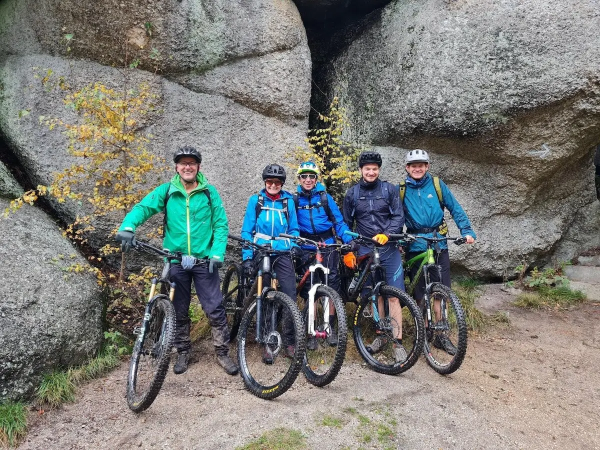 Fünf Radfahrer stehen mit ihren Mountainbikes vor großen Felsen; nasser Boden, herbstliche Bäume und Outdoor‑Szene im Gelände. | © DAV Markt Schwaben