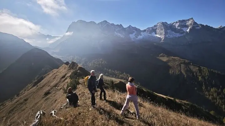 Vier Personen bei einer gemeinsamen Wanderung auf einem sonnigen Bergrücken mit Blick auf die Alpen – ein Moment aktiver Gemeinschaft in der Natur. | © DAV Markt Schwaben · Foto: Matzinger · 2025