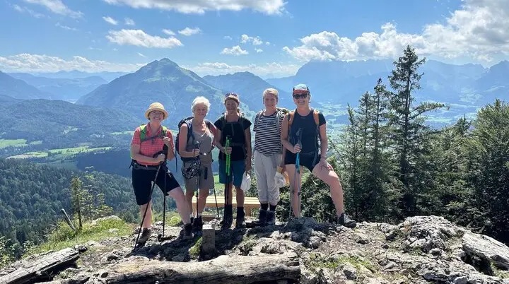 Eine Gruppe von fünf Wanderern steht auf einem felsigen Aussichtspunkt mit Wanderstöcken, umgeben von einer beeindruckenden Berglandschaft mit grünen Tälern und bewaldeten Hängen. Die klare Luft und die weite Aussicht symbolisieren Abenteuer, Gemeinschaft und die Freude am Wandern – Jetzt Mitglied werden und Teil des Alpenvereins werden! | © DAV Markt Schwaben | Foto Elke Kressirer