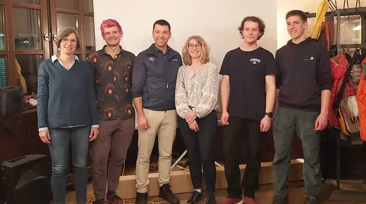 Sechs Personen, der neu gewählte Vorstand, stehen in einem Raum mit einer Leinwand und Holzfußboden. | © DAV Markt Schwaben | Foto Martina Straub