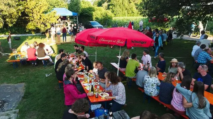 Besucher tanzen auf einer gelben Holzplattform, während andere an Tischen sitzen und der Kletterturm im Hintergrund sichtbar ist. | © DAV Markt Schwaben | Foto: Thomas Schäffler