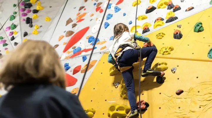 Eine Trainerin sichert ein junges Mädchen in einer Kletterhalle | © DAV / Jens Klatt